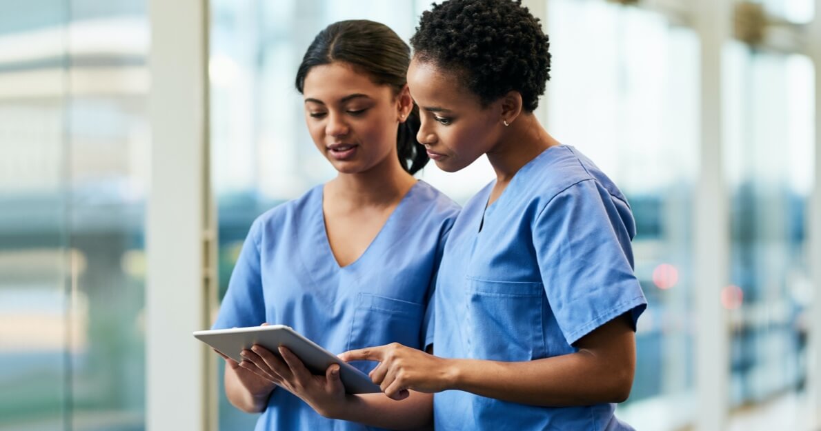 Two nurses conversing and looking at a tablet